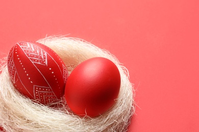 Photo of Nest with red painted Easter eggs on table, closeup. Space for text