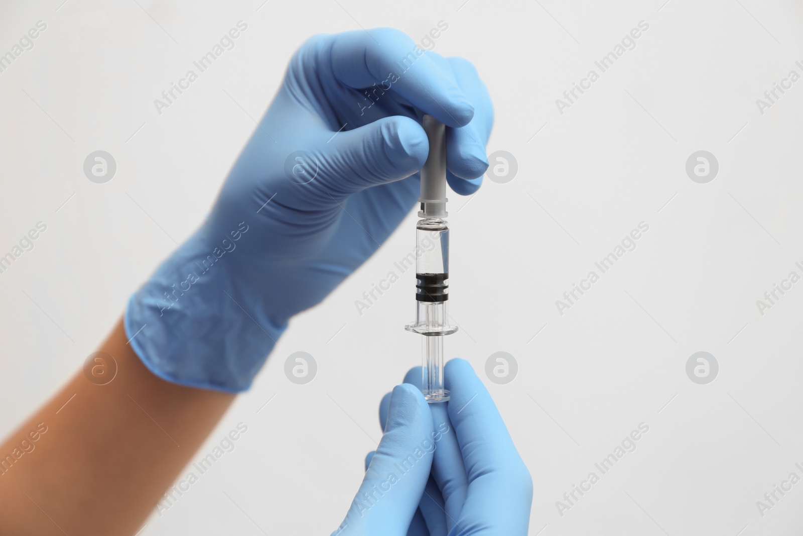 Photo of Doctor holding syringe with COVID-19 vaccine on light background, closeup