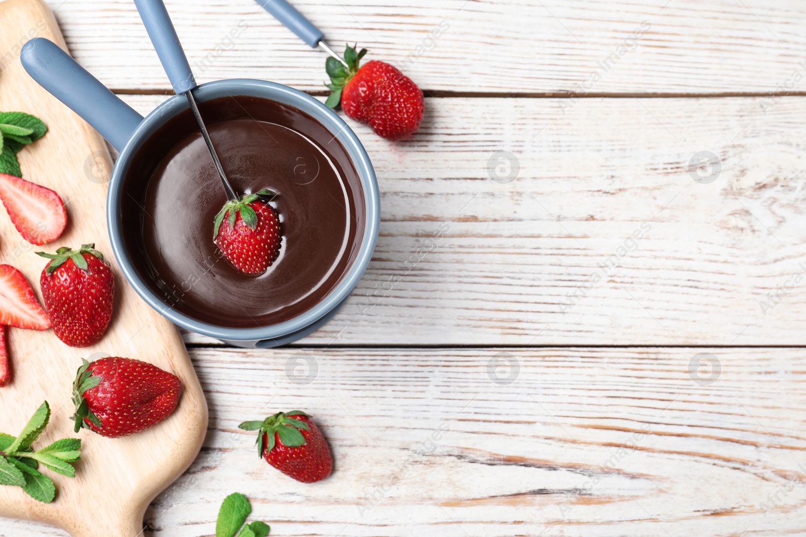 Photo of Chocolate fondue with strawberries and marshmallow on wooden table