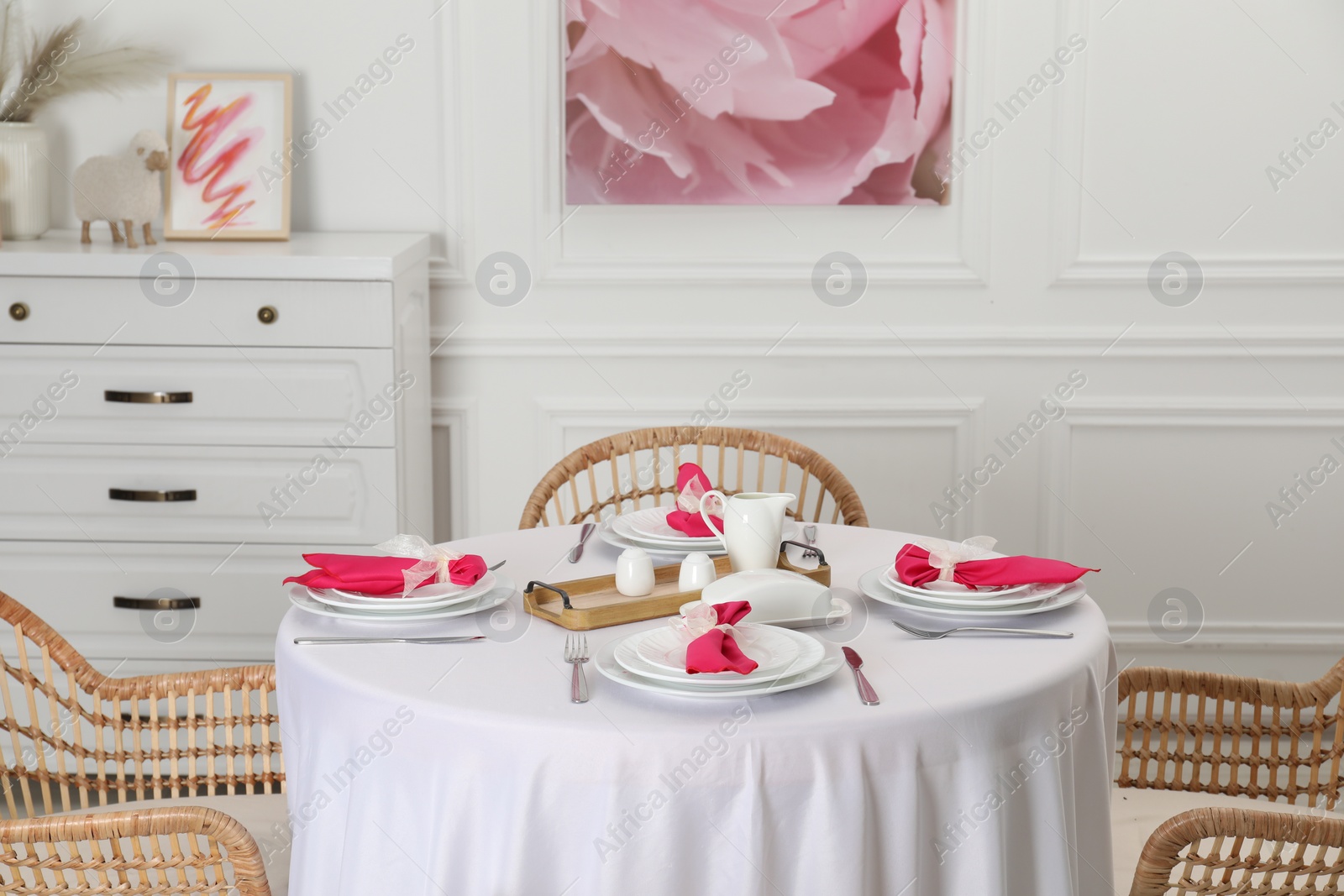 Photo of Color accent table setting. Plates, cutlery and pink napkins in dining room