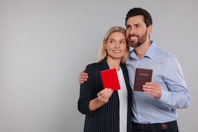 Photo of Immigration. Happy couple with passports on gray background, space for text