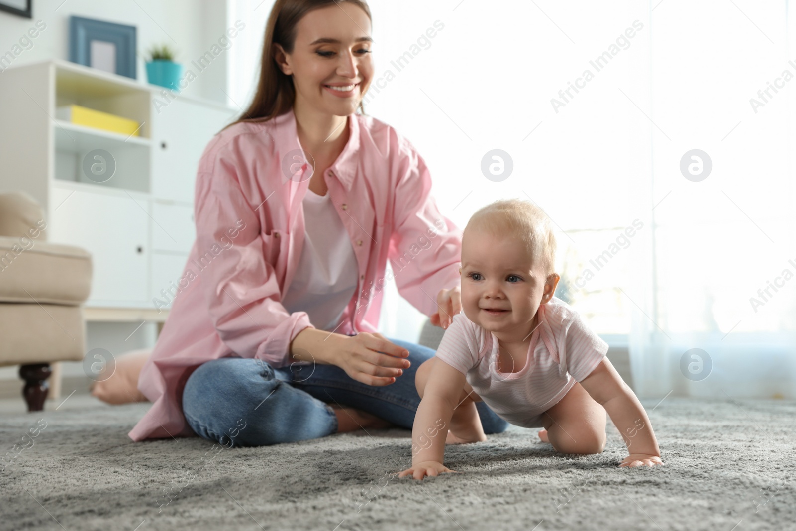 Photo of Adorable little baby crawling near mother at home