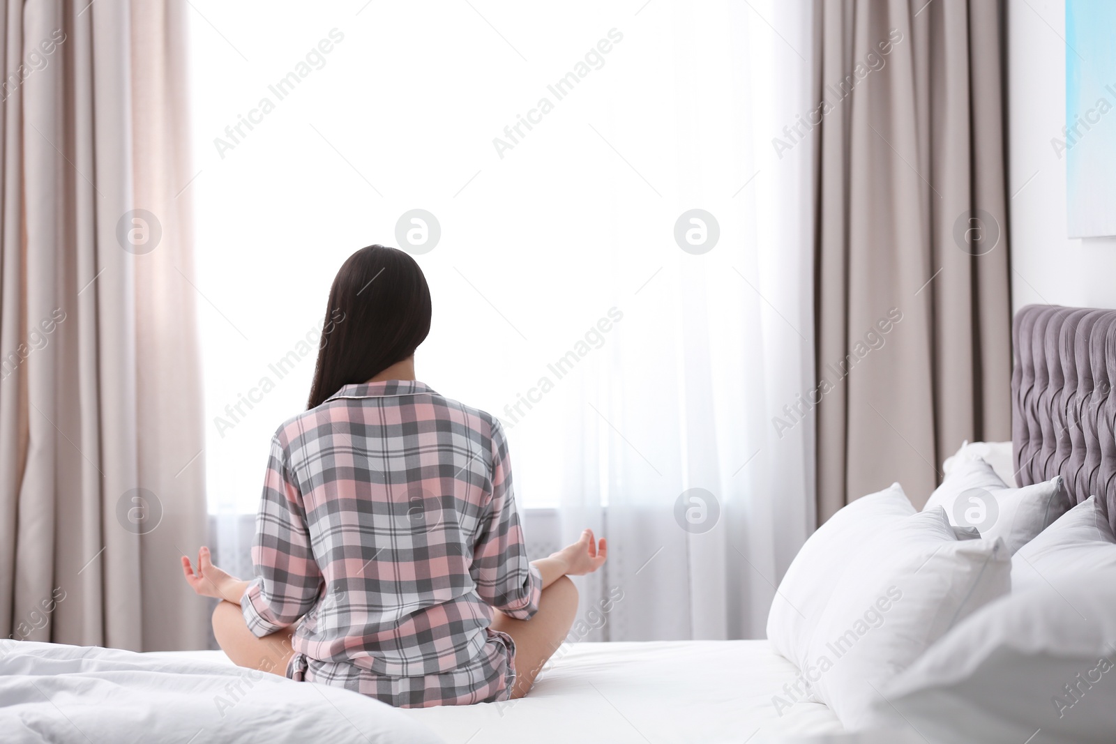 Photo of Young woman meditating on bed at home. Zen concept