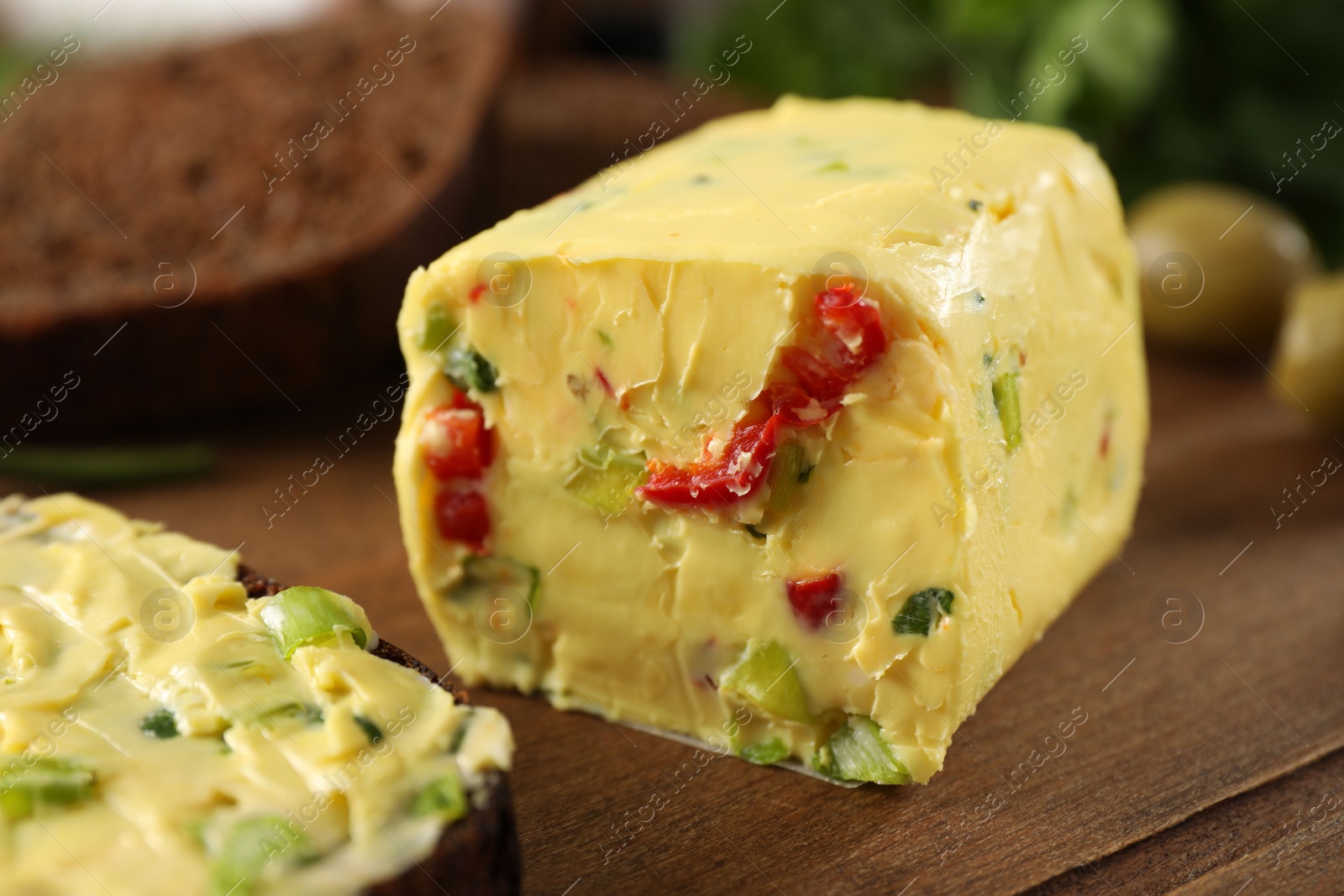 Photo of Tasty butter with green onion and chili pepper on wooden board, closeup