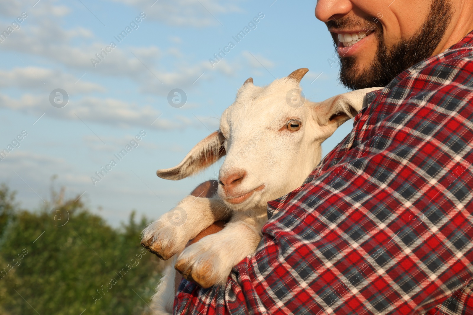 Photo of Man with baby goat at farm, closeup. Animal husbandry