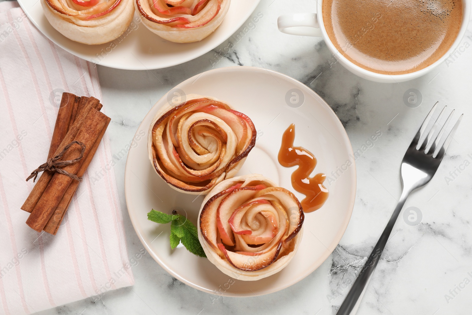 Photo of Freshly baked apple roses served on white marble table, flat lay. Beautiful dessert