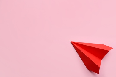 Red paper plane on pink background, top view. Space for text