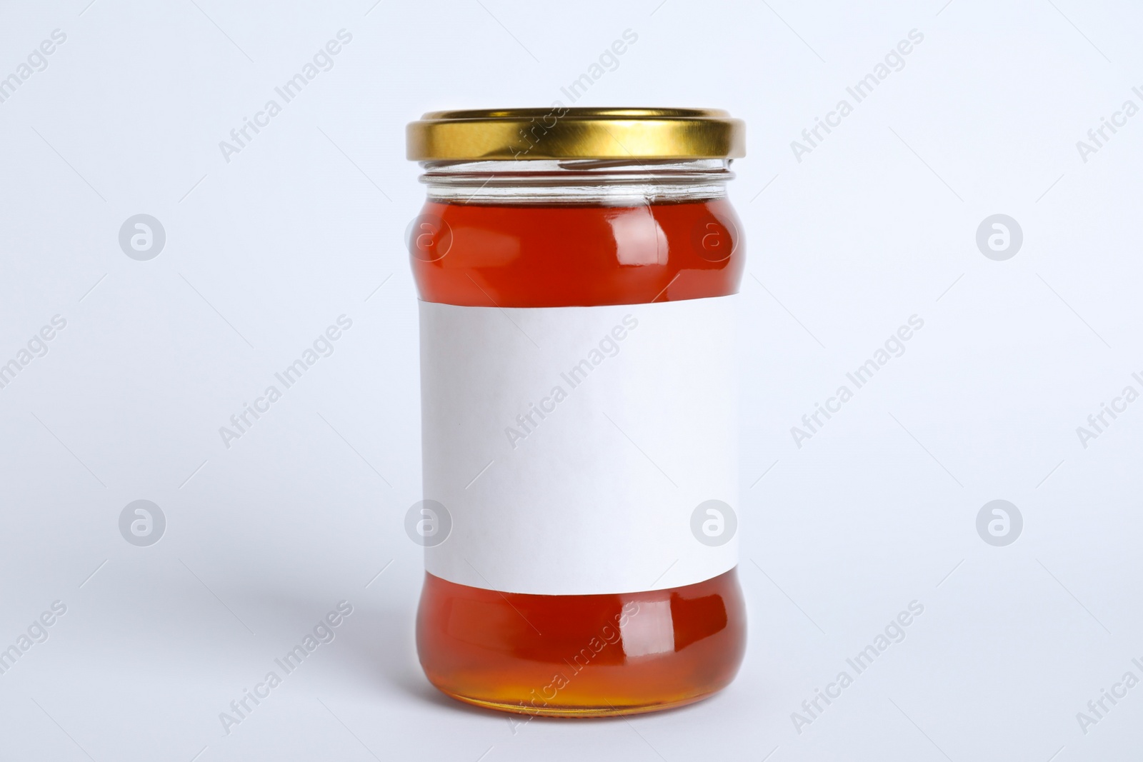Photo of Glass jar of wildflower honey with blank label isolated on white