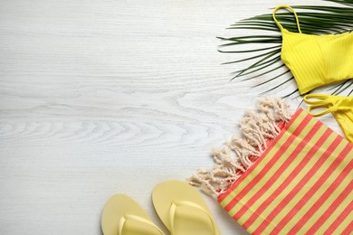 Photo of Beach towel, swimsuit and flip flops on white wooden background, flat lay. Space for text