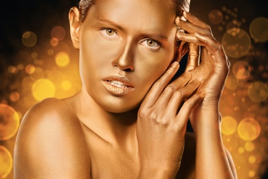 Portrait of beautiful lady with gold paint on skin against blurred lights