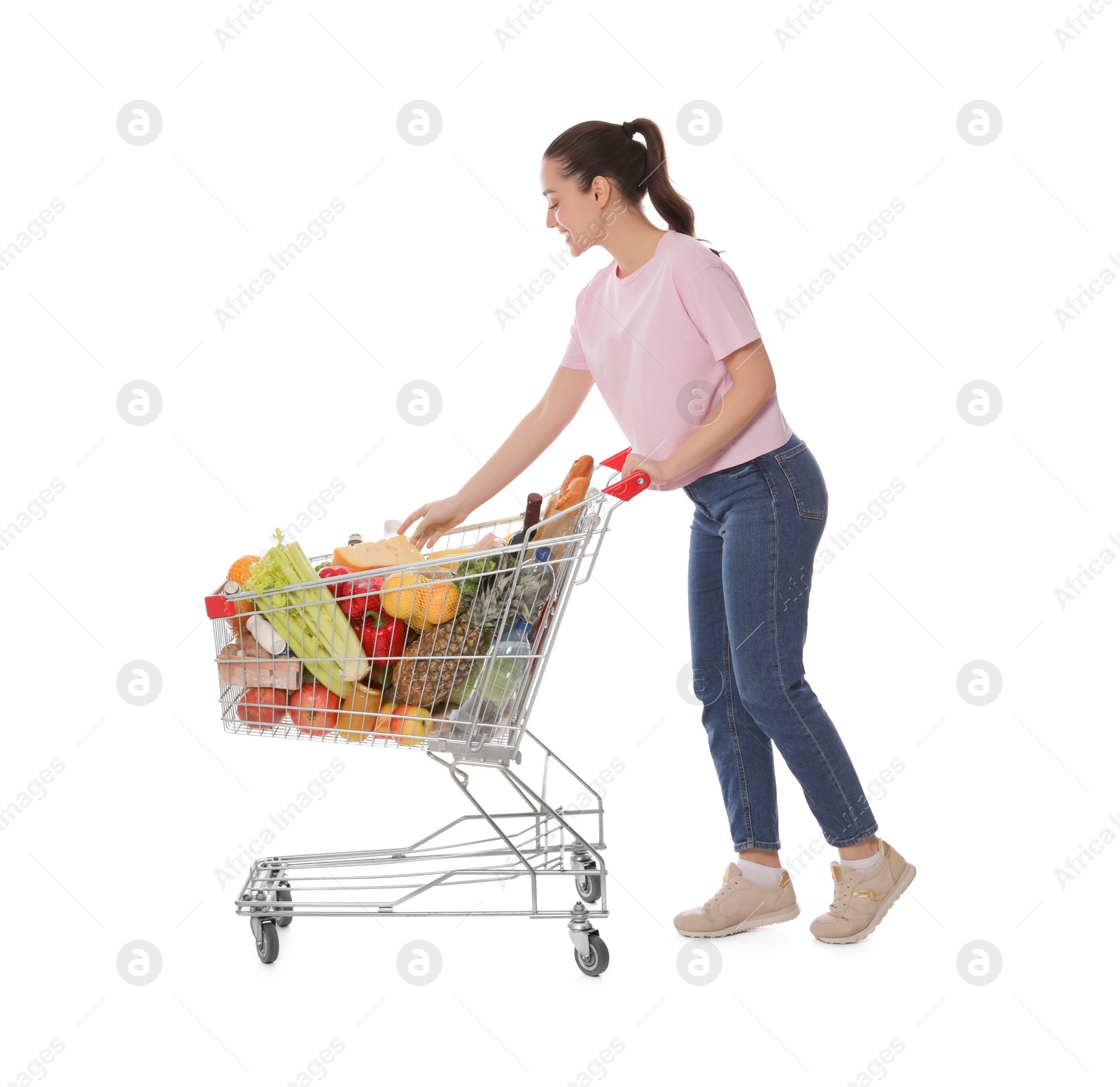 Photo of Happy woman with shopping cart full of groceries on white background