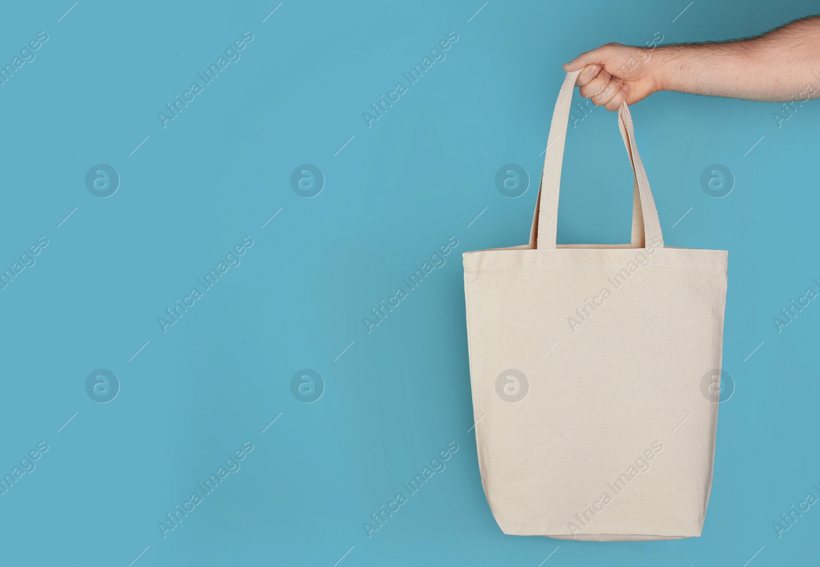 Photo of Man holding cotton shopping eco bag on color background. Mockup for design