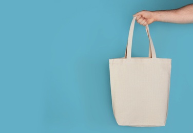 Photo of Man holding cotton shopping eco bag on color background. Mockup for design