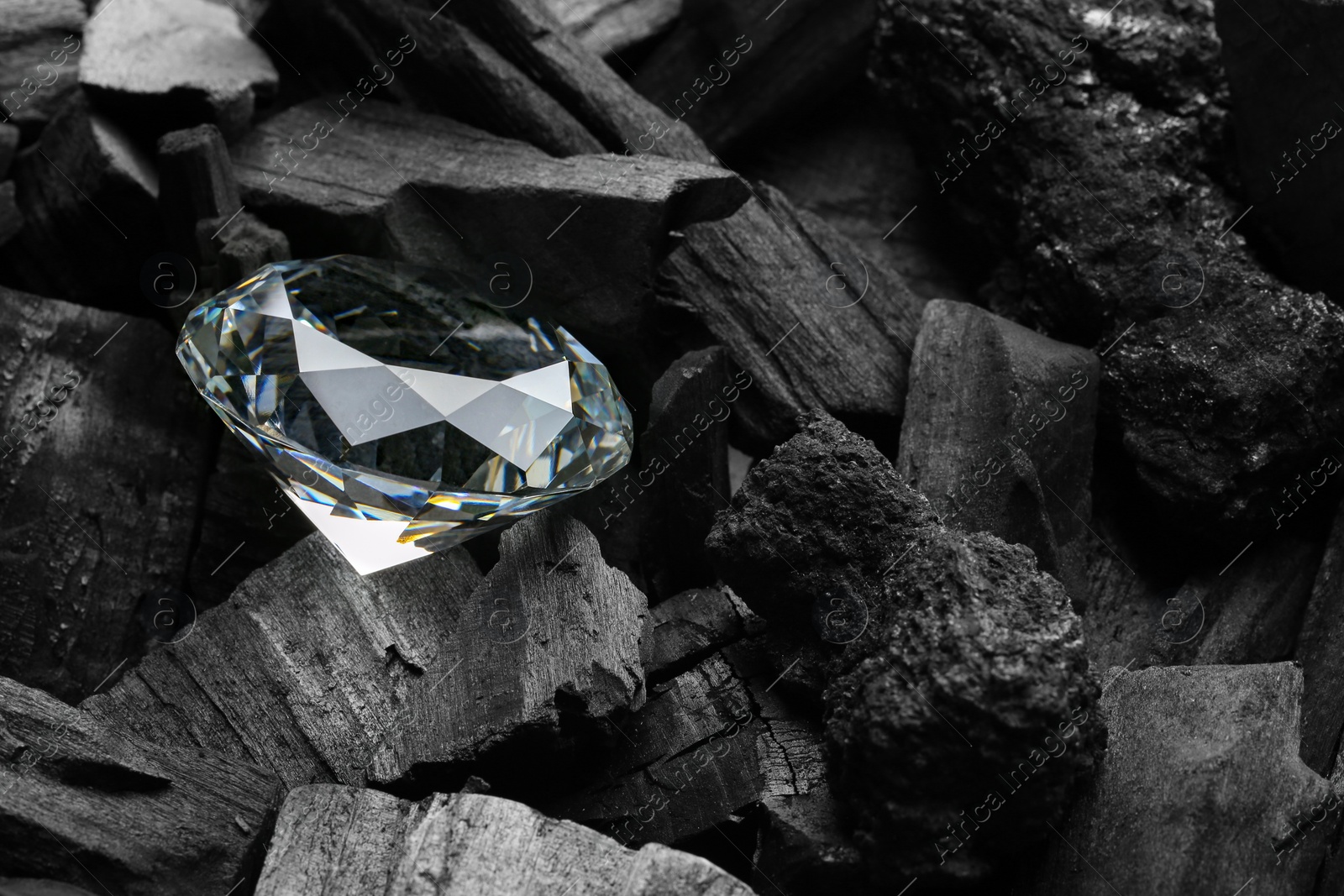 Photo of Beautiful shiny diamond on coal, closeup view