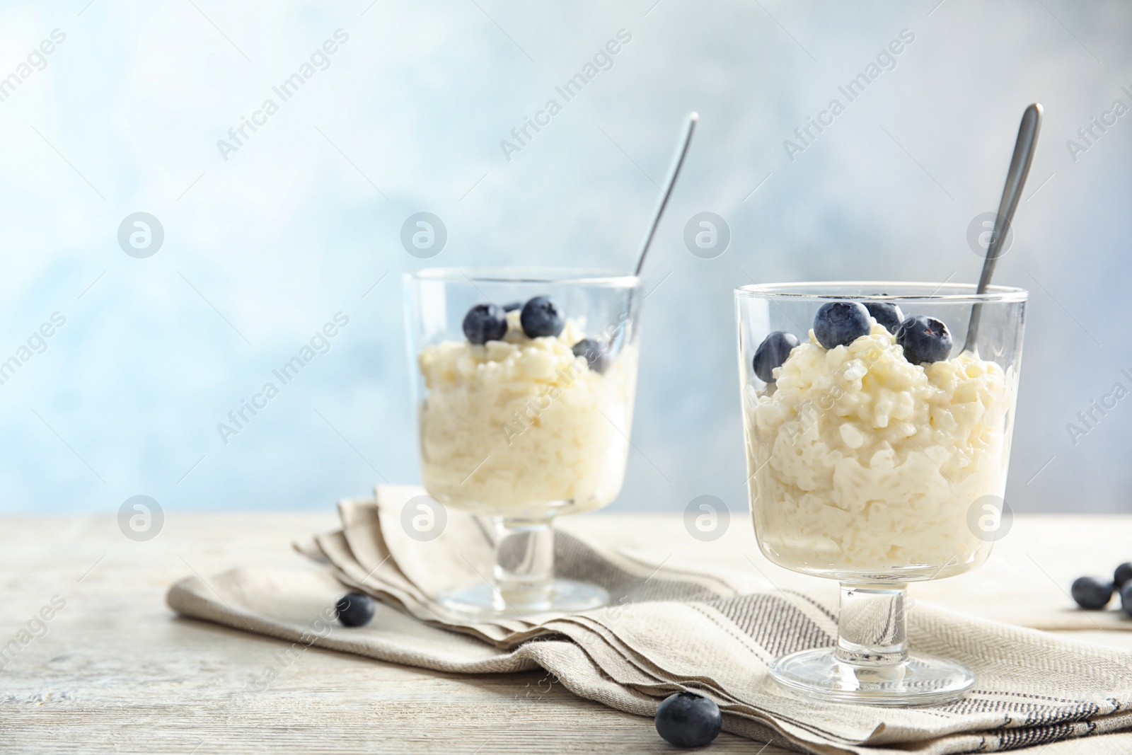 Photo of Creamy rice pudding with blueberries in dessert bowls on table. Space for text