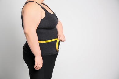 Photo of Overweight woman with measuring tape on light background