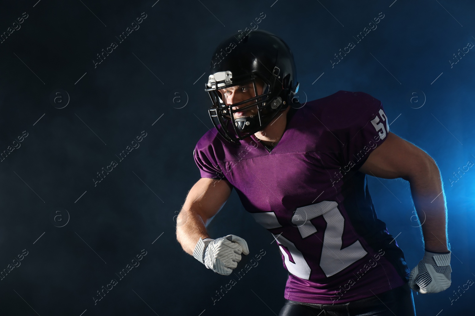 Photo of American football player wearing uniform on dark background. Space for text