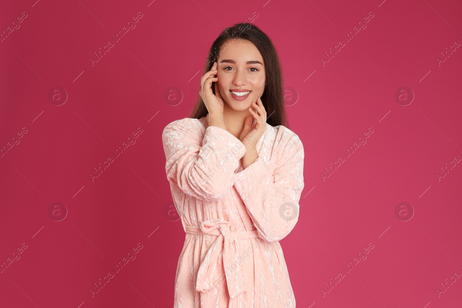 Photo of Beautiful young woman in bathrobe on crimson background