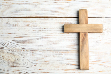 Christian cross on white wooden background, top view with space for text. Religion concept