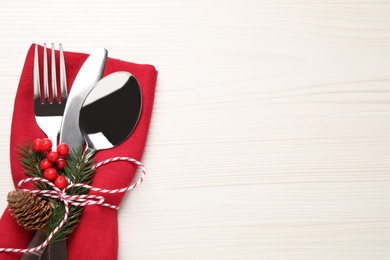 Cutlery set and festive decor on white wooden table, top view with space for text. Christmas celebration