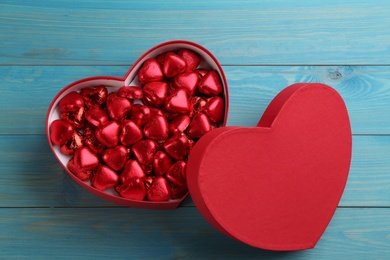 Heart shaped chocolate candies in gift box on blue wooden table, top view. Valentines's day celebration