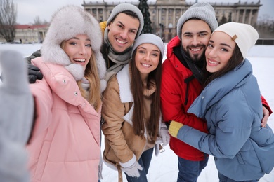 Photo of Happy friends taking selfie at ice skating rink outdoors