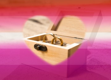 Image of Double exposure of lesbian flag and golden wedding rings in box