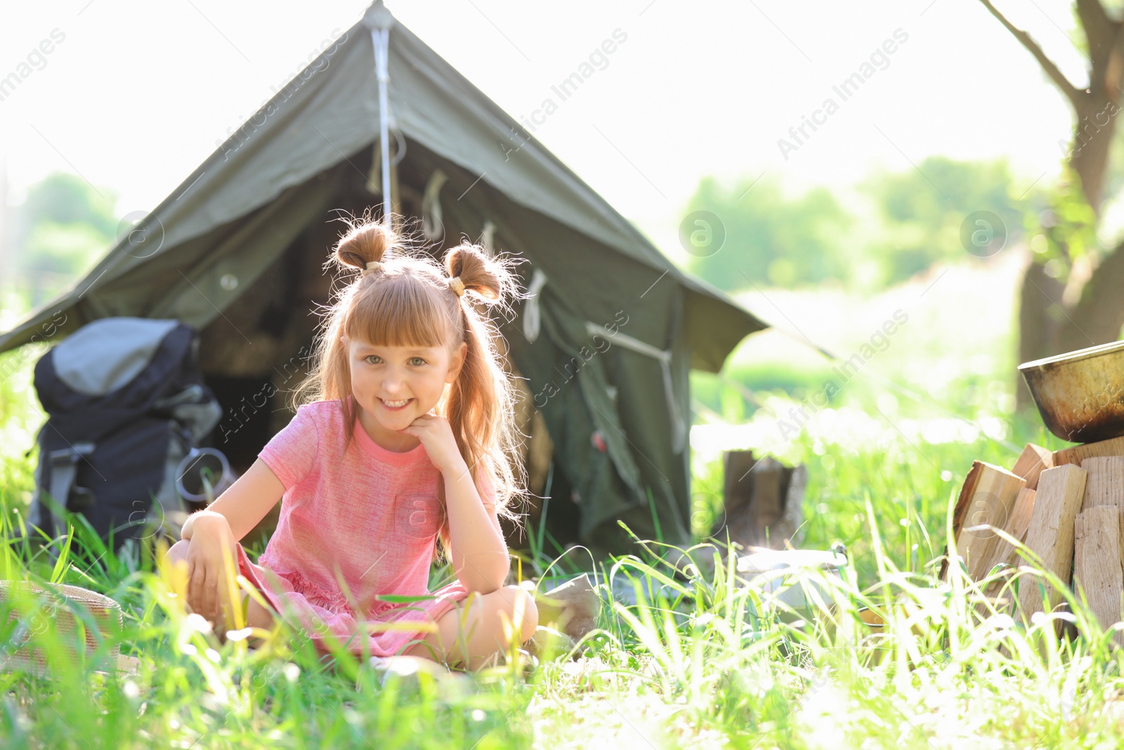 Photo of Little girl near tent outdoors. Summer camp