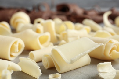 Photo of Tasty white chocolate curls on table, closeup.
