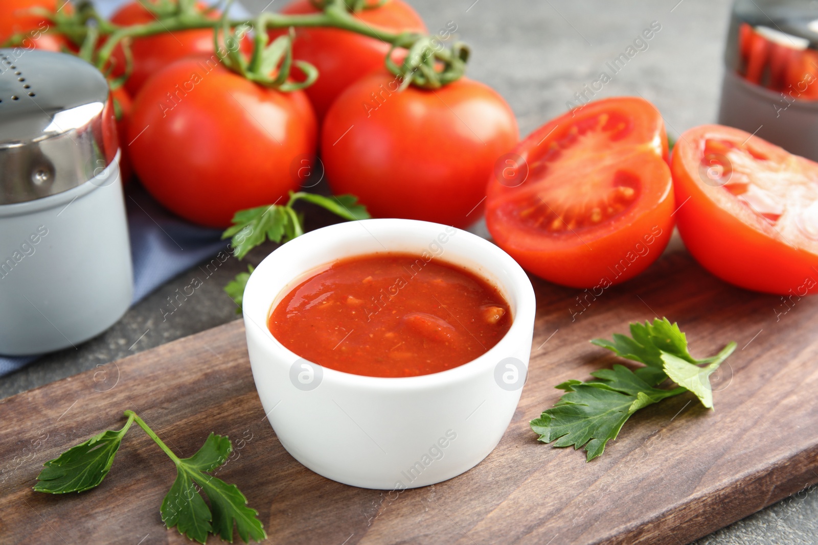 Photo of Composition with bowl of tomato sauce and parsley on table