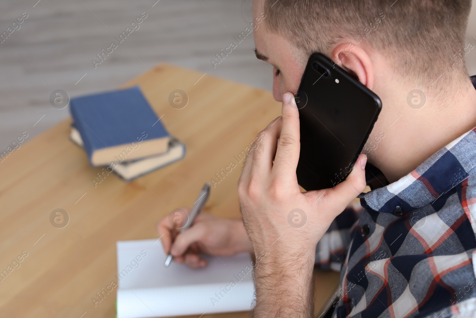 Photo of Young man talking on mobile phone at desk. Home office