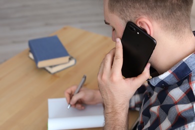 Young man talking on mobile phone at desk. Home office