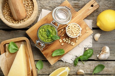 Photo of Delicious pesto sauce and ingredients on wooden table, flat lay