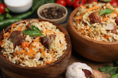 Photo of Delicious pilaf with meat and carrot in bowls on table, closeup