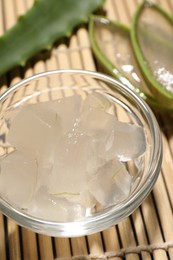 Photo of Aloe vera gel and slices of plant on bamboo mat, closeup