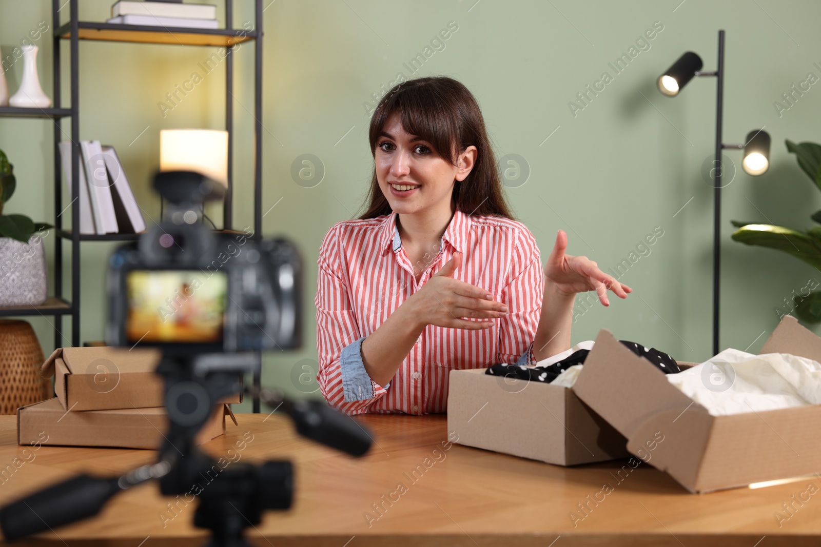 Photo of Smiling fashion blogger recording video while talking about clothes at home