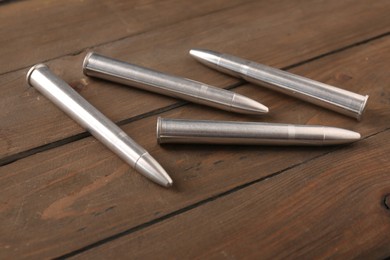 Many metal bullets on wooden table, closeup