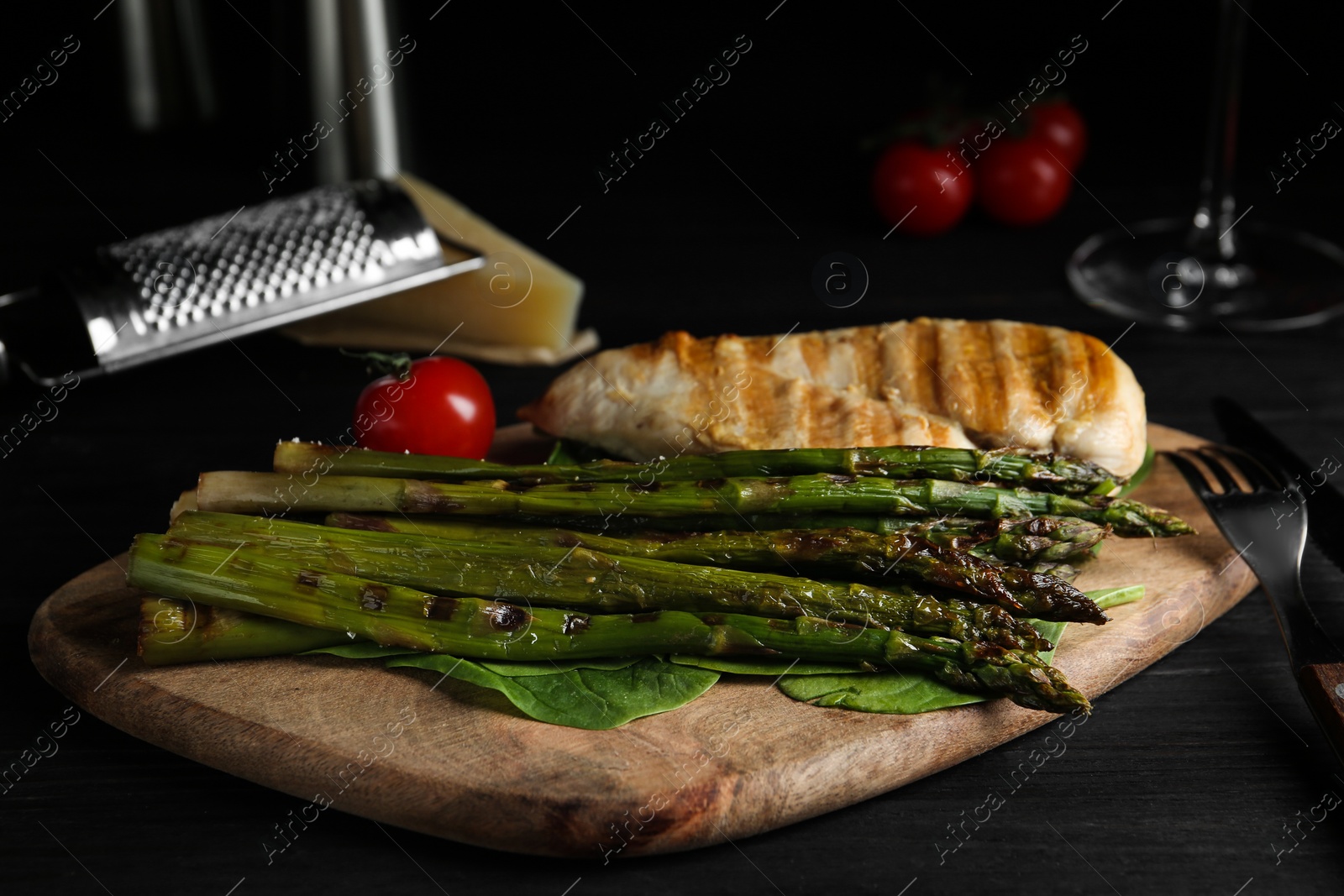 Photo of Tasty grilled chicken fillet served with asparagus on wooden board
