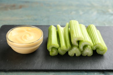 Photo of Celery sticks with dip sauce on slate plate, closeup