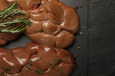 Fresh raw kidneys with rosemary and thyme on black table, top view