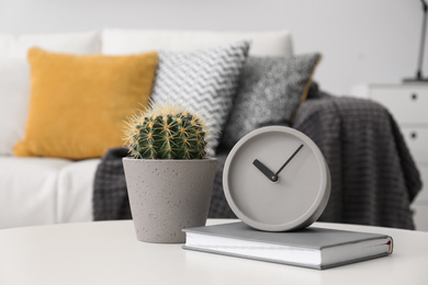 Photo of Clock and cactus on white table in stylish living room