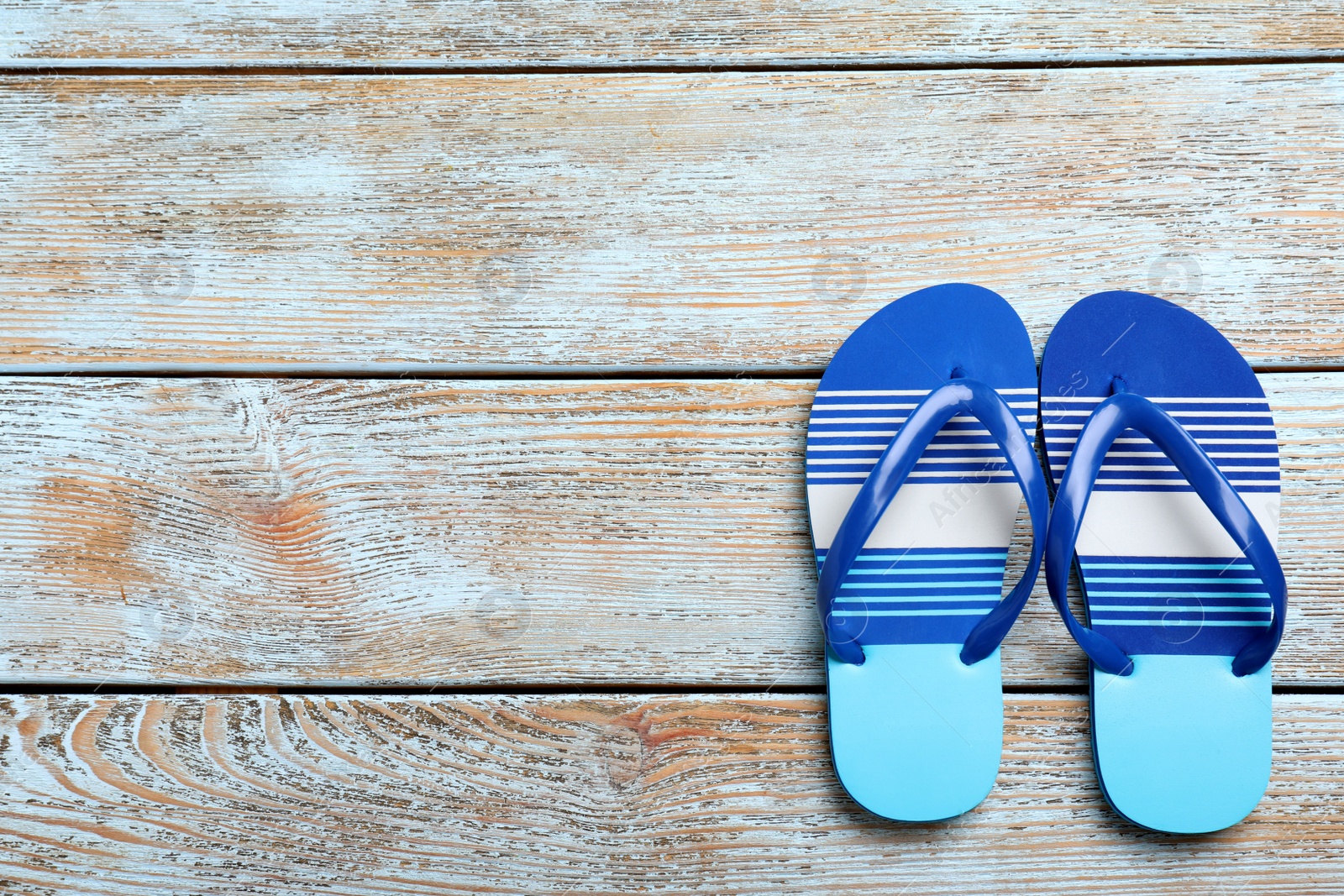 Photo of Stylish flip flops on light wooden background, flat lay. Space for text