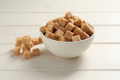 Photo of Brown sugar cubes on white wooden table