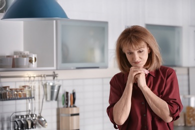 Photo of Senior woman suffering from depression on kitchen at home
