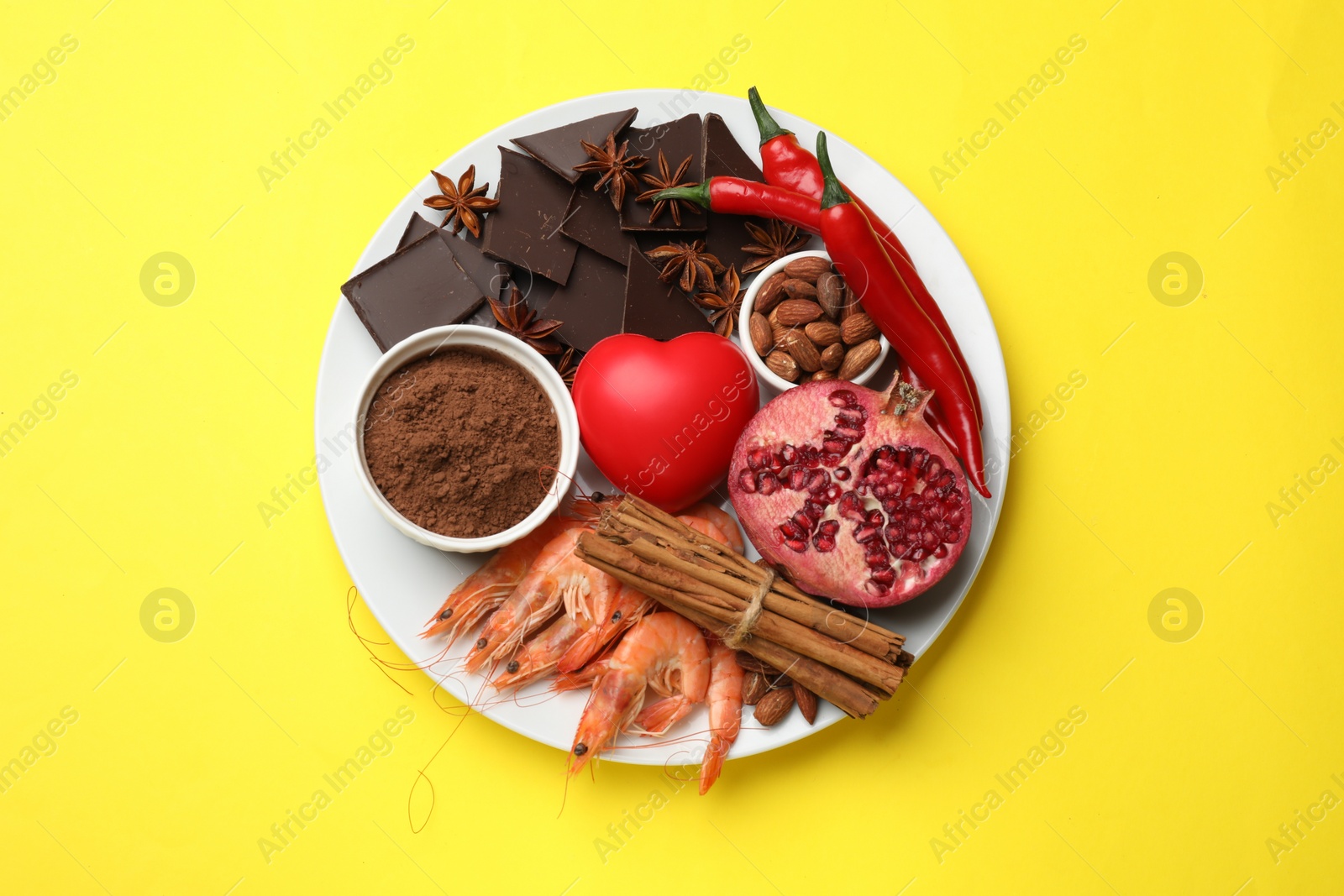 Photo of Natural aphrodisiac. Different products and heart model on yellow background, top view