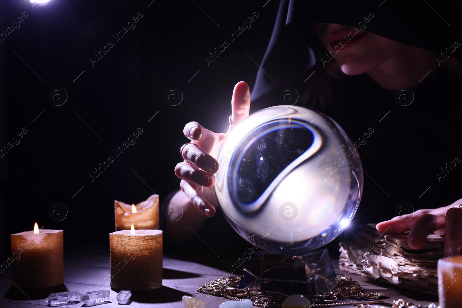 Photo of Soothsayer using crystal ball to predict future at table in darkness, closeup. Fortune telling