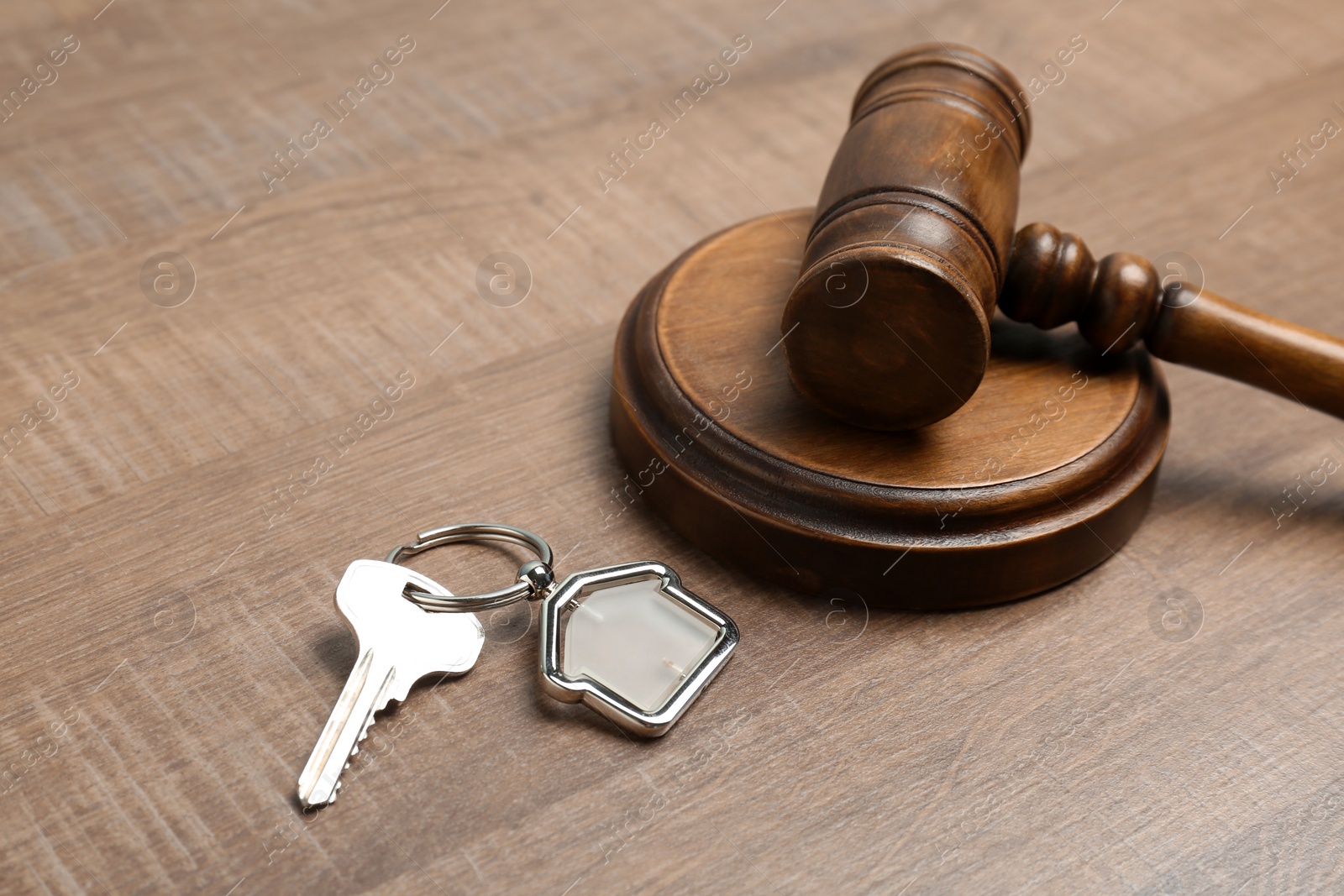 Photo of Judge gavel and house key on wooden background. Estate law concept