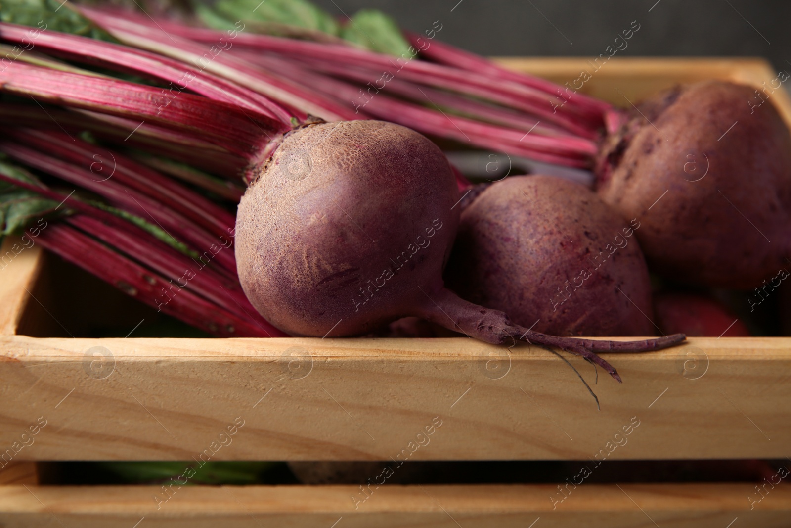 Photo of Wooden crate with fresh organic beets, closeup