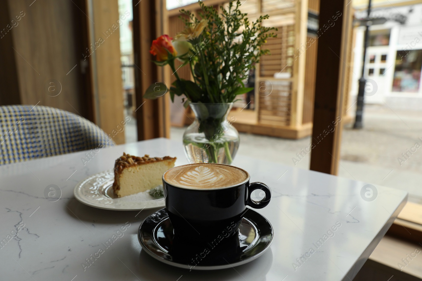 Photo of Cup of fresh coffee and dessert on table in cafeteria