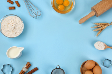 Photo of Flat lay composition with raw eggs and other ingredients on light blue background, space for text. Baking pie